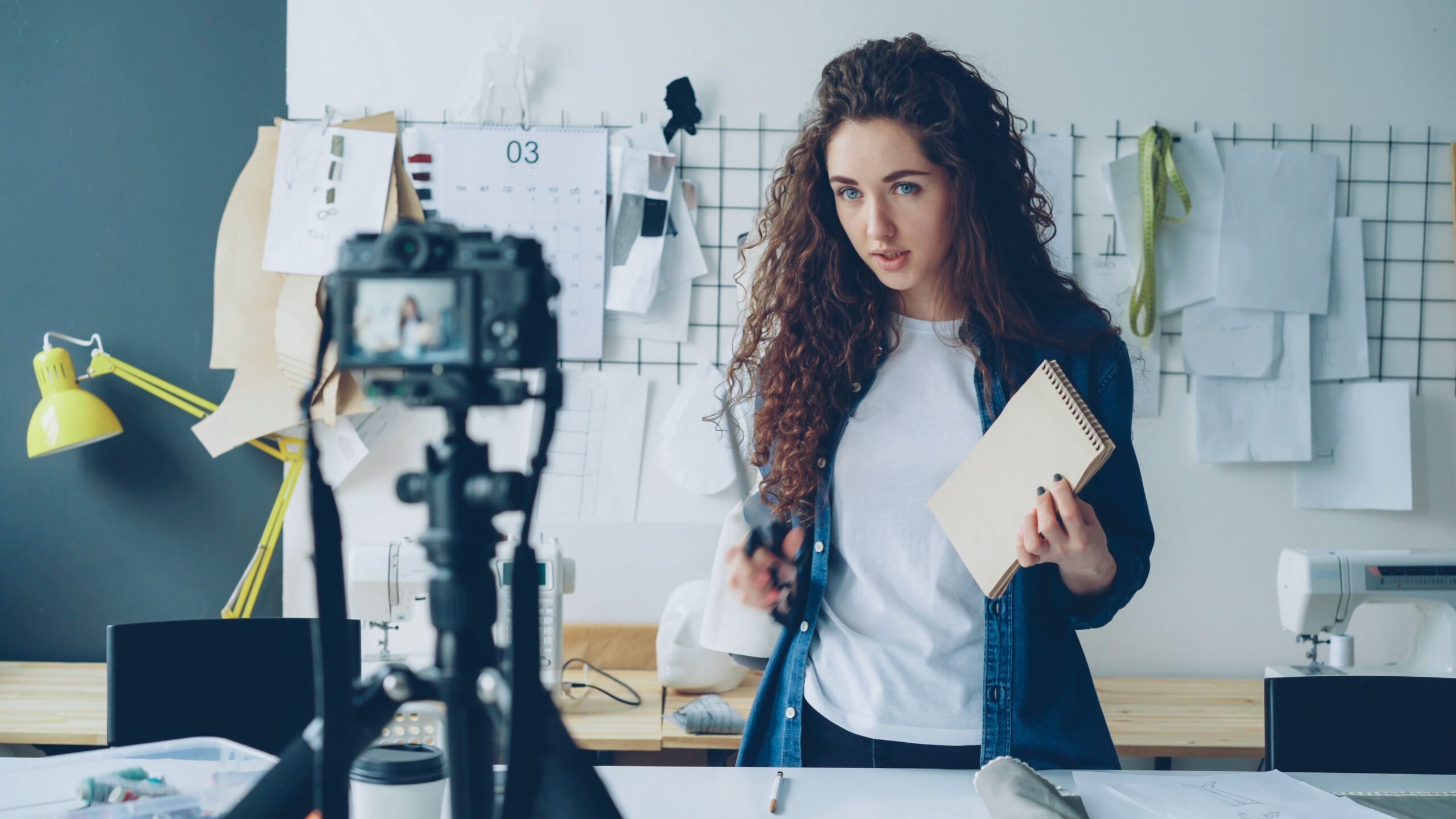 Young fashion designer records a video tutorial in her studio, focused on creativity and design.