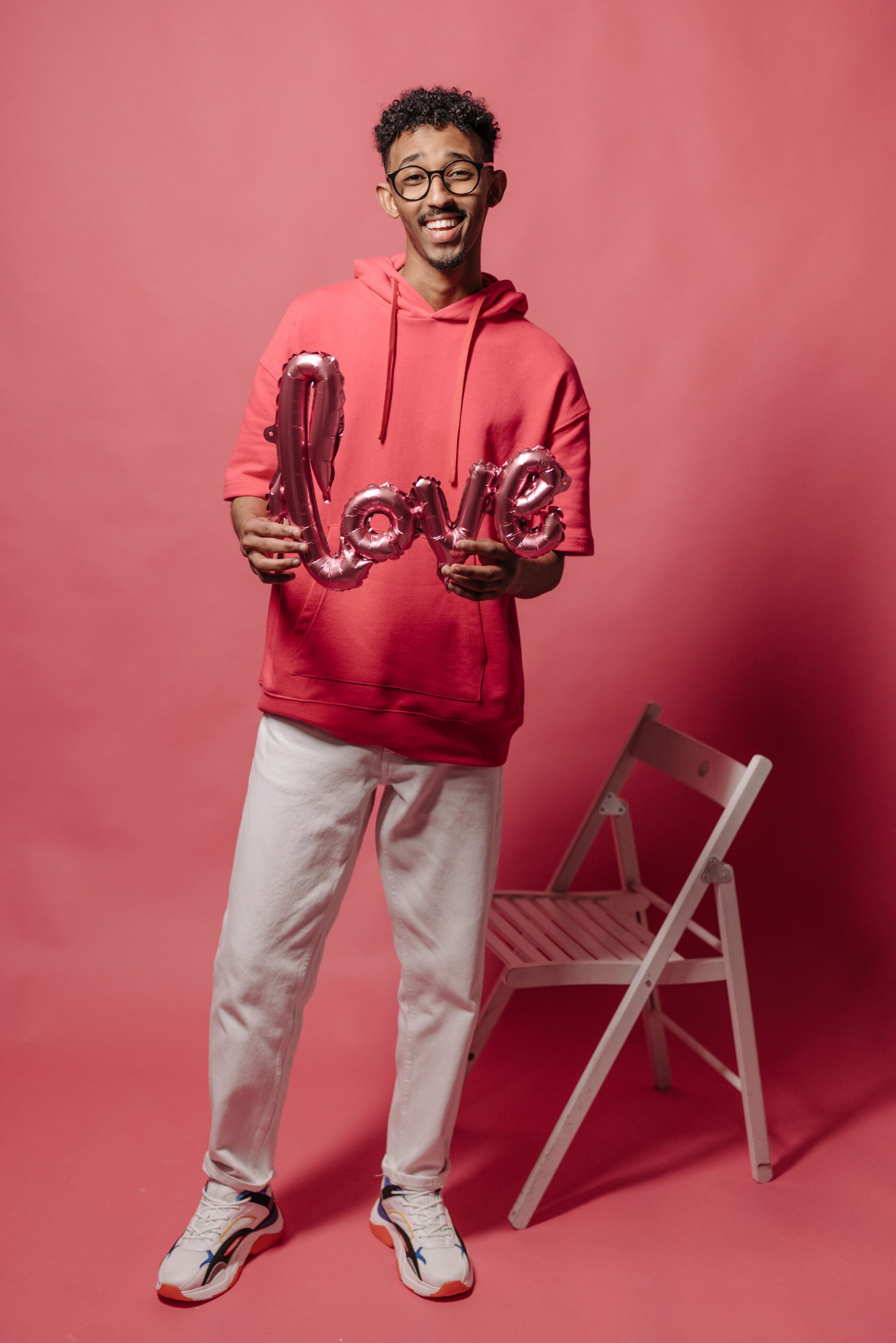 Smiling man with love balloon in a studio setting against a red background.